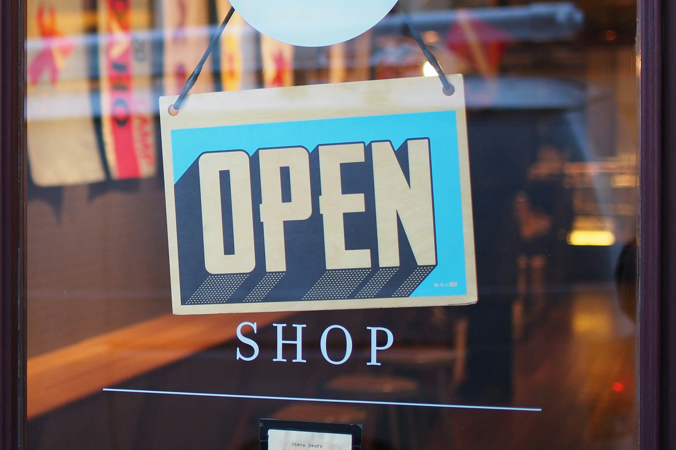 A door with a sign that says open and below it shop, representing that the shop is now open.